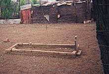 square grave marked by rectangle brick outline on dirt
