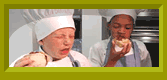 Brian and Taylor in chef hats and aprons, eating.