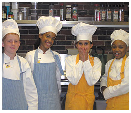 Brian, Taylor, Julia, and Khalil wearing aprons and chef hats.
