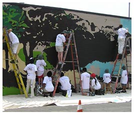 Kids and adults painting a mural.