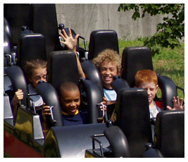 Anna, Noah, Khalil, and Brian waving from a roller coaster.