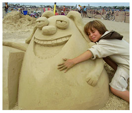 Sam hugging a sand sculpture of Ruff on the beach.