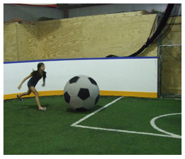 Talia is about to kick a really big soccer ball.