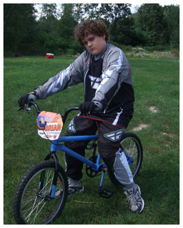Brian sits on a bicycle wearing a racing uniform.