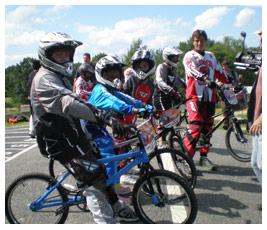 Brian, Bethany, and Talia sit on bikes at the start of a race.