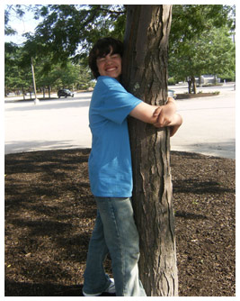 Isaac smiles as he hugs a tree.