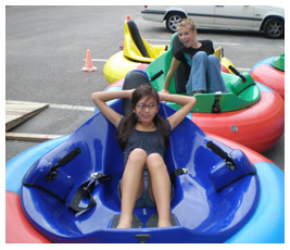 Liza and Talia lounge in bumper boats in a parking lot.