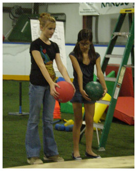 Liza and Talia about to drop two balls onto a board.