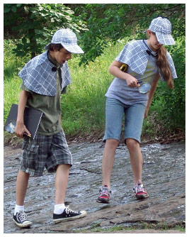 Marco and Emmie wear detective outfits and search the ground.