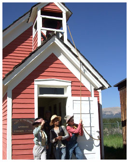 Jay, Marc, and Emmie outside an old-fashioned schoolhouse.