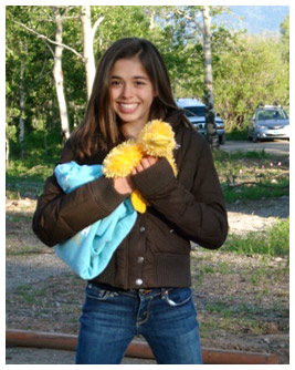 Rubye holds a toy duck in a nature park, with mountains in the distance.