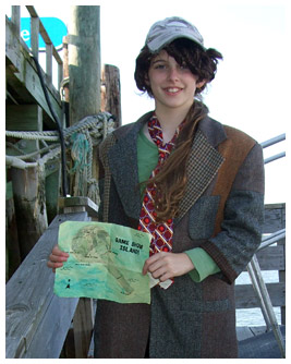 Emmie wears a man's suit and holds a map for Gameshow Island.