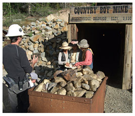Marc, Jay, and Emmie stand outside a mine and look at a map.