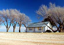 Dry farmland surrounds a lonely house