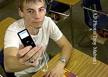 A student in a classroom holds up his iPod.