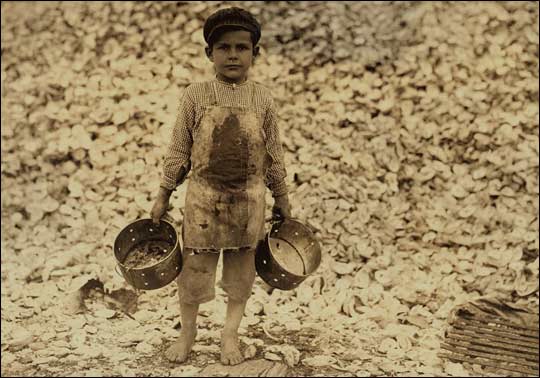 A five-year-old boy next to a pile of oyster shells.