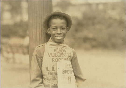 A newspaper boy wearing a hat.